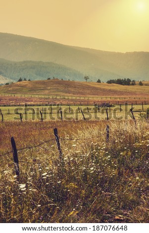 old fence on meadow in sunset mountains in the background