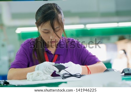 Female conveyor worker in white gloves assembling electronic device on Chinese factory