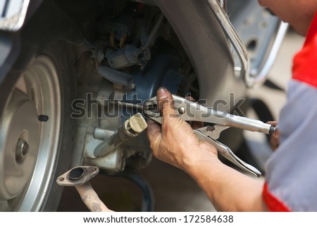 mechanic repairing motorbike holding adjustable wrench