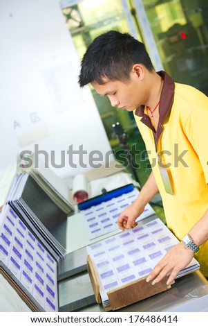 worker of plastic cards factory prepares pvc lamination for hot press