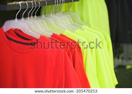 red and yellow shirts on hangers in modern fashion boutique
