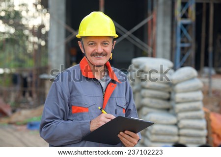Joyful builder in helmet with file in hands on a building site