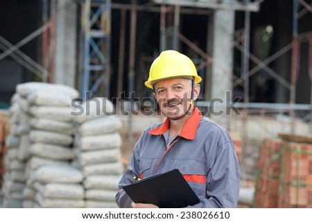 Joyful builder in helmet with file in hands on a building site