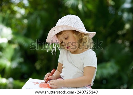 Beautiful little girl draws by felt-tip pen
