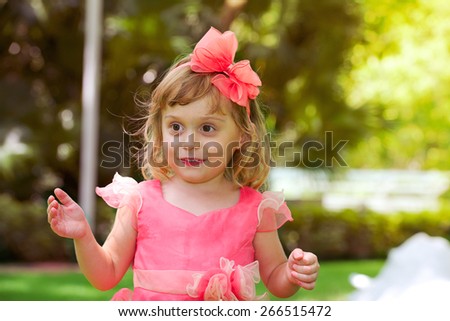 Happy surprised little beautiful girl in pink dress