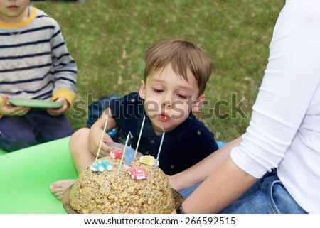 Handsome boy blows out the candles on the cake for a birthday celebration