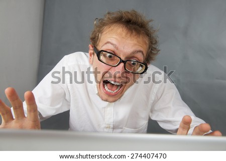 Cute young shocked man with laptop.