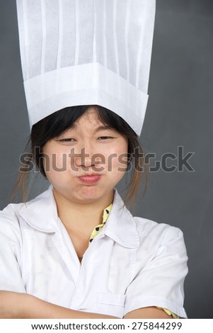 Pretty Asian chef cook girl expresses emotions on her face. Vertical photo