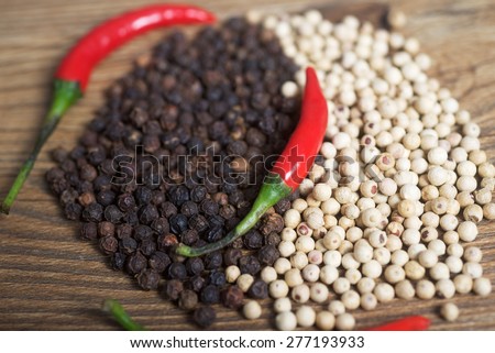Red chilly peppers with black and white peppers background