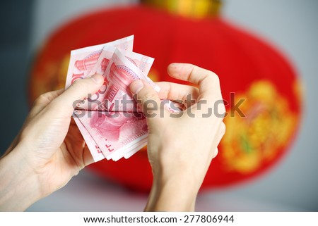Man counting Chinese money in hands, Chinese lantern background