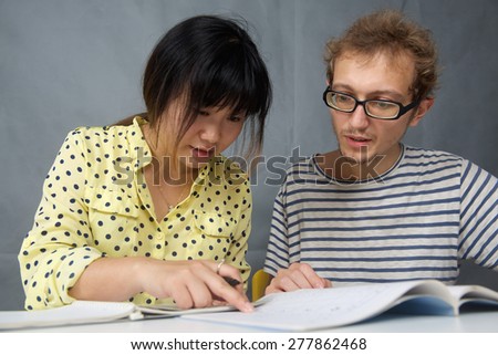 Caucasian happy young man talking with a Chinese girl is language teacher