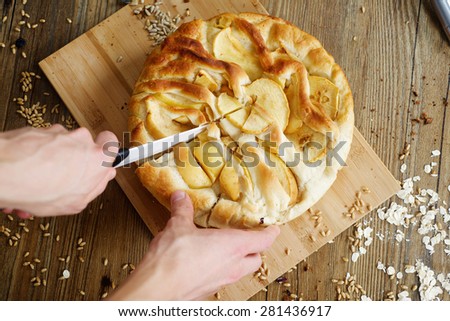 Baker cuts homemade apple pie on table