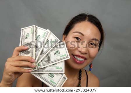 Portrait of cheerful Asian young woman with dollars