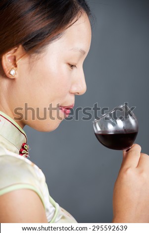 Beautiful girl in Chinese traditional dress smell glass of wine