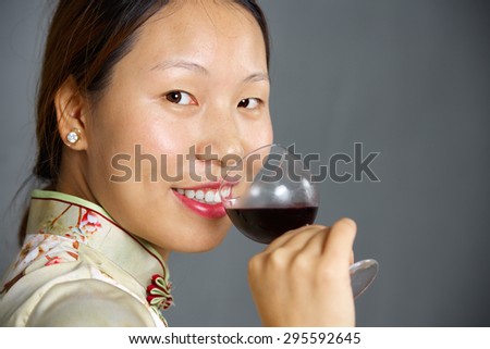 Beautiful girl in Chinese traditional dress smell glass of wine