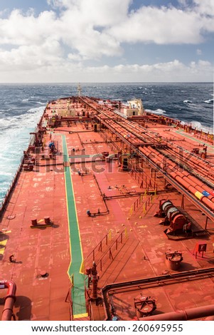 Big red deck of tanker ship under cloudy sky, while windy weather - stock photo.