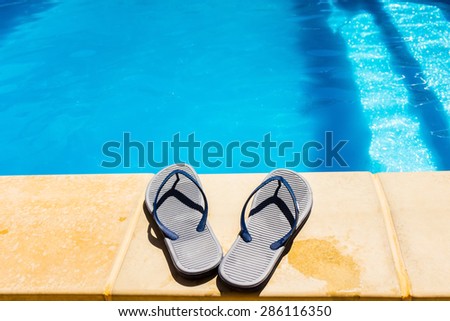 Couple of sand shoes on a border of swimming pool.
