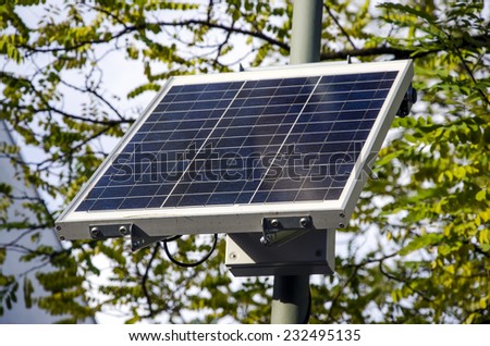 sustainable small solar panel with branches and leaves of trees in the background for the environment