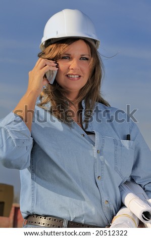 Female construction worker holding blueprints while talking on the phone