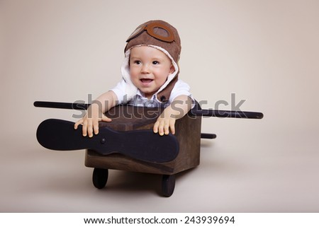 Beautiful baby boy inside a wooden airplane wearing an aviator hat