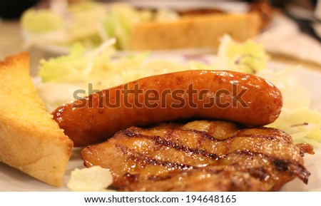 Grilled Sausages, Grilled Pork and Vegetables with A Piece of Toast on The Side in A Restaurant