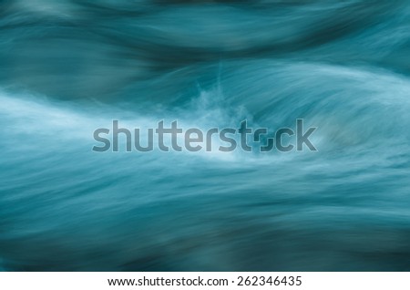Abstract image of fast running water waves. A DSLR photo of fast running water.  The blue water waves and white splashes form unique abstract lines.