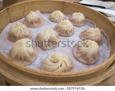 Basket of xiaolongbao (steamed meat bun), famous asian food. Chinese dumplings on bamboo steamer.