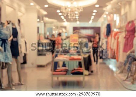 De focused/Blur image of a dress store with customers and dressed mannequins.