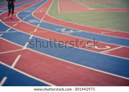 De focused/blurred image of a female runner on running track with numbers from 1 to 3.