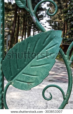 Wrought iron railing. Shape of leaf with saw teeth edge. Dark green color.