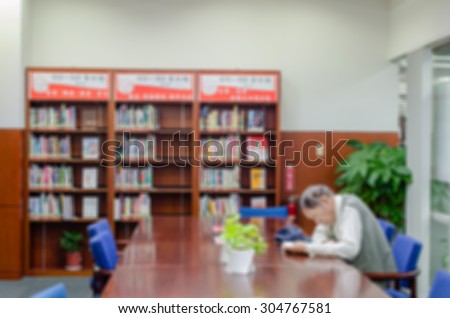 De focused/Blurred image of an old man reading a book in library.