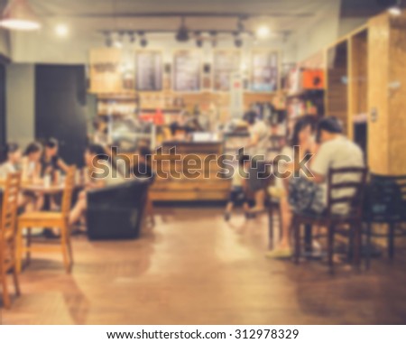 De focused/Blurred image of people sitting in cafe chatting, using cell phone and buying coffee. Vintage effect.