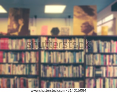 De focused/Blur image of a bookstore. Books one bookshelves and two write portraits on shelves. Retro effect.