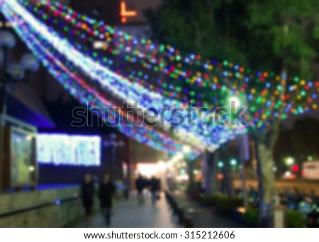 De focused/Blurred image of people walking on street at night during Christmas season.