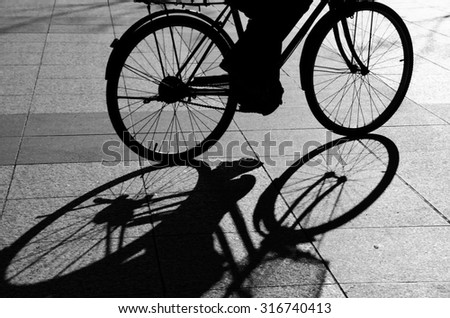 Black and white image of shadow of a cyclist. Motion blur.