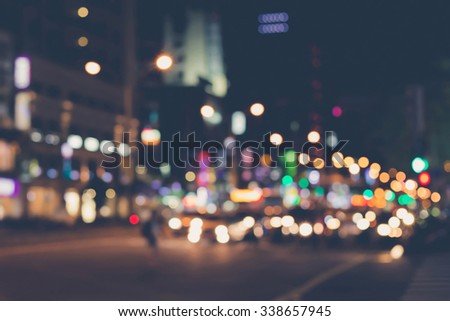 De focused/blur image of city at night. A man crossing the road. De focused, blurred urban abstract traffic background.