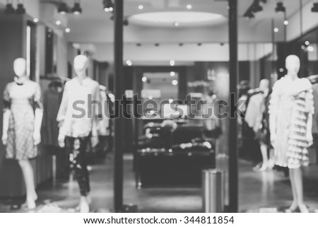 Blurred image of boutique window with dressed mannequins. Boutique display window with mannequins in fashionable dresses. Black and white image.