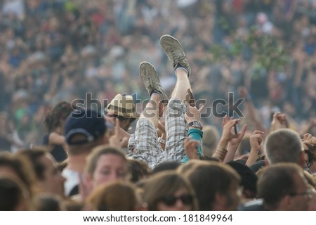 A young man raised by the crowd during a concert with the legs only visible