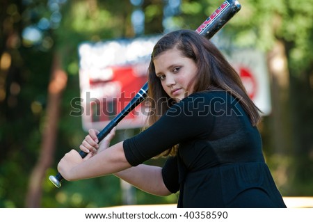 A teenage girl is ready to hit a softball