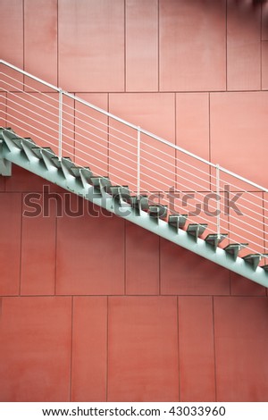 A metal stair in front of a red background