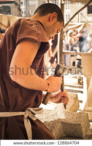PONTEVEDRA - SEPTEMBER 1: A mason works a piece of granite stone under the eyes of curious during the Medieval Celebration of September 1, 2012, in Pontevedra, Spain.