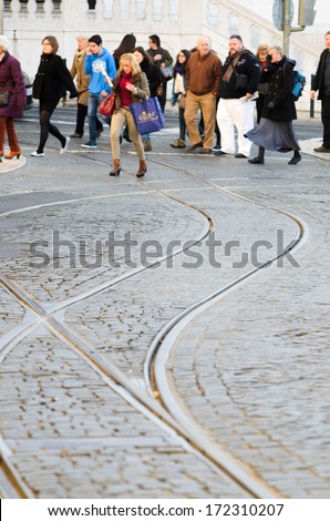 LISBON, PORTUGAL - DECEMBER 5, 2013: A group of people crossing the tram tracks on a busy street in Lisbon.