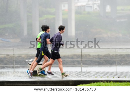 Pontevedra, SPAIN - MARCH 2, 2014: People practice track and field one day of heavy rain, on a track for running and walking in the city of Pontevedra.