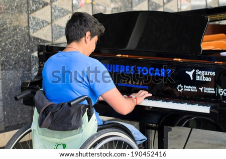 BILBAO, SPAIN - APRIL 4, 2014: A girl in a wheelchair plays a grand piano during music initiative \