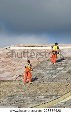 SANTIAGO DE COMPOSTELA, SPAIN - JULY 11, 2014: Few workers with harnesses, cleaned the roof of one of the buildings that make up The City of Culture of Galicia (Spain)