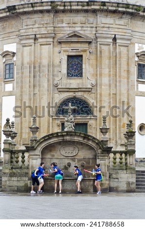 PONTEVEDRA,  SPAIN - AUGUST 2, 2014: A group of young people having fun, throwing water at a fountain in the historic old town.