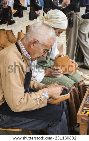 PONTEVEDRA, SPAIN - SEPTEMBER 6, 2014: A shoemaker manufactures boots, in medieval festival held each year in the historical district of the city.