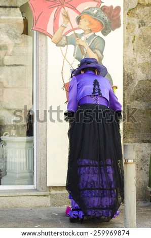 CUNTIS, SPAIN - SEPTEMBER 13, 2014: A woman sweeps the outside of your clothing business, clothed in the Roaring 20, the Feast of the Belle Epoque held in the village every year.