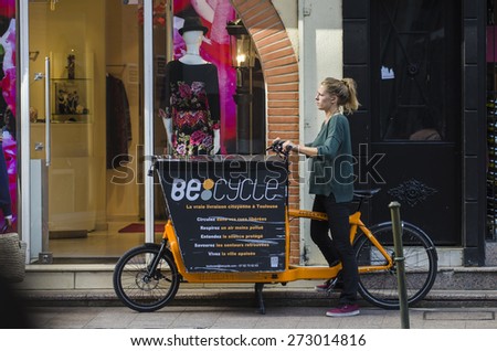 TOLOUSE, FRANCE - OCTOBER 4, 2014: A woman driving a bicycleÂ of distribution in the historic city center.