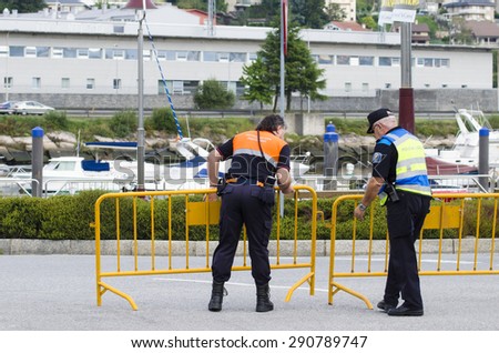 PONTEVEDRA, SPAIN - OCTOBER 19, 2014: A police officer and a member of civil protection placed a fence before holding a marathon.